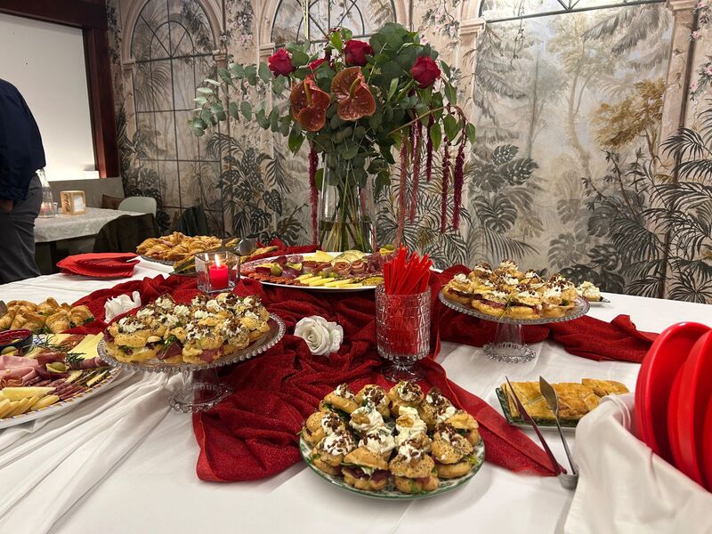 Allestimento rosso con composizione floreale e catering nella sala riservata